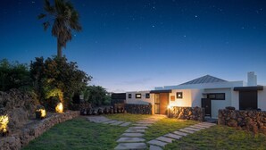 A modern house with a stone pathway leading to the entrance, surrounded by lush greenery and a clear night sky. - Jeju Staysosoheon Dokchae Pension (Jeju City)