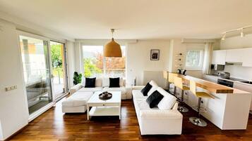 A modern living room with a sofa, coffee table, and a kitchen area with a bar.