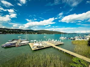 A marina with boats docked, a pier with sun loungers, and a clear blue sky.
