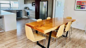 A modern kitchen with dark cabinets, stainless steel appliances, and a wooden dining table with four chairs. - Jestalong Villa (Robe)