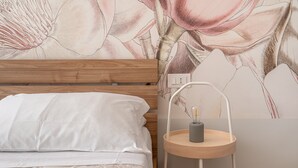 Quarto com cabeceira de madeira, roupa de cama branca e mesa de cabeceira com abajur.