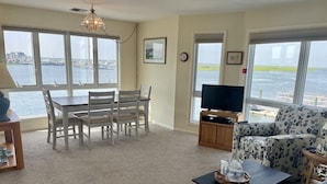 Ein Wohnzimmer mit Esstisch, Stühlen, einer Couch, einem Fernseher und Blick auf das Wasser.