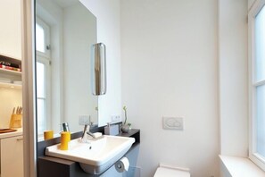 A modern bathroom with a white sink, mirror, and a window. - ipartment Köln City (Cologne)