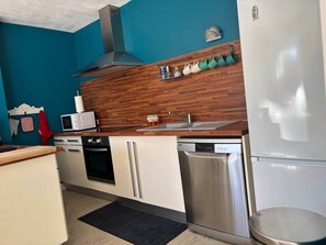 A compact kitchen with a microwave, oven, dishwasher, and a stainless steel refrigerator.