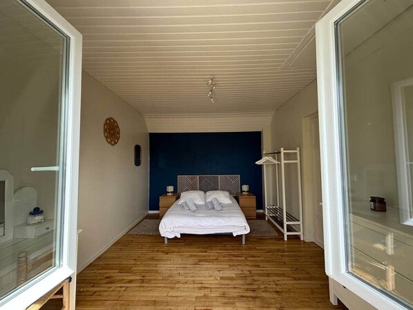 Une chambre à coucher avec un lit, des tables de chevet, une armoire et une fenêtre.