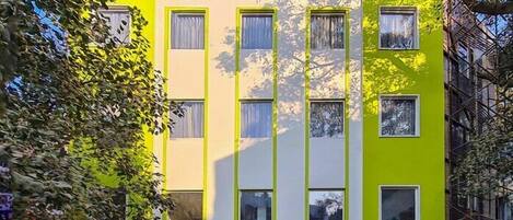 A hotel named "HOTEL LE ROI express" with a bright yellow facade, multiple windows, and social media icons displayed above the entrance.