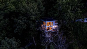 A modern treehouse with multiple levels, surrounded by dense forest.