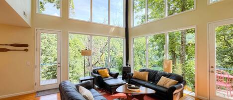 A spacious living room with a large window, a fireplace, and a view of the outdoors.