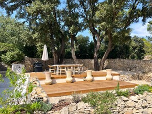 Enjoy al fresco dining on the patio, surrounded by lush greenery and a grill for outdoor cooking.