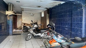 Une pièce où se trouvent deux motos, un sol carrelé et un mur recouvert de carreaux bleus.