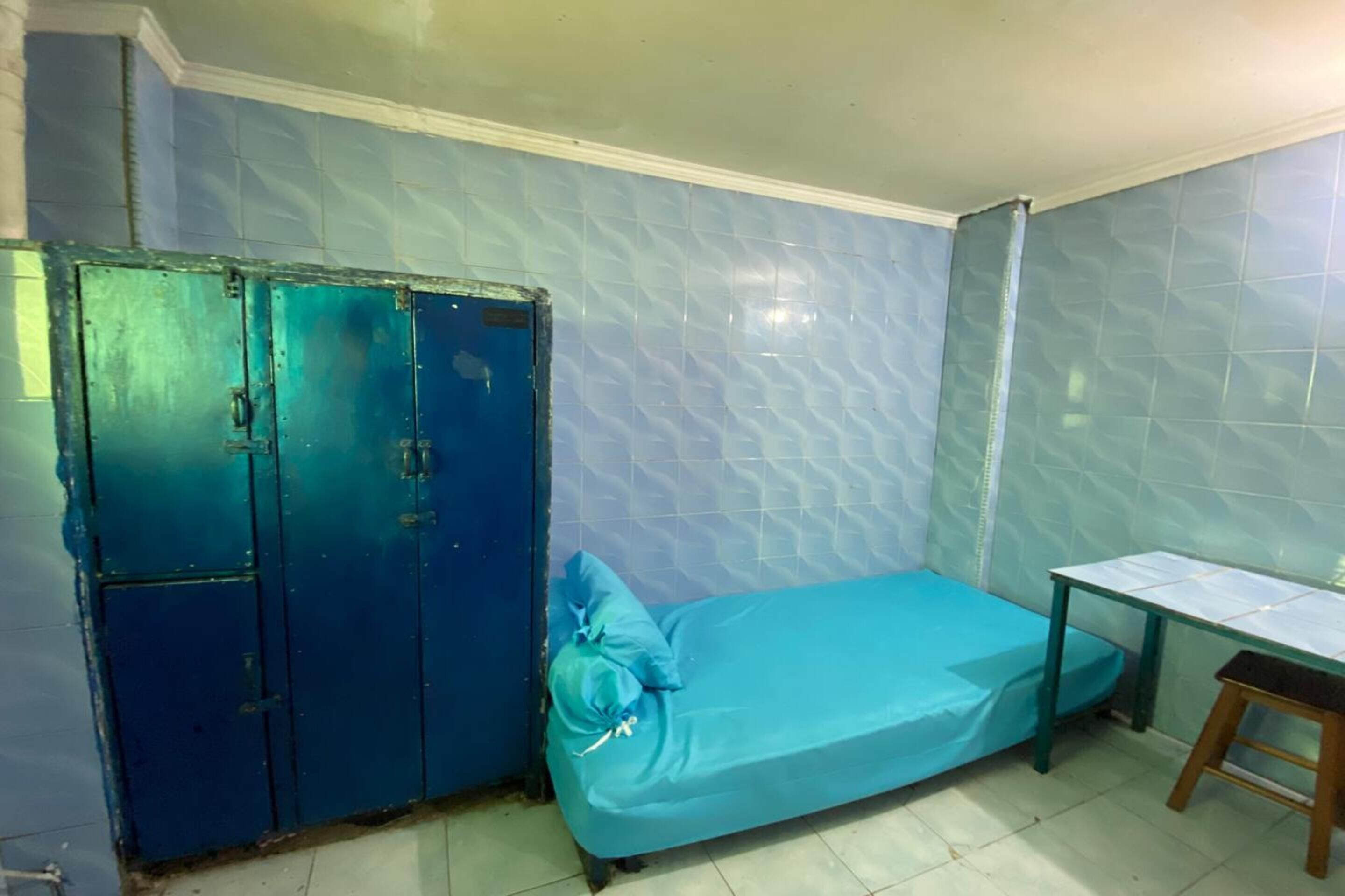 Una habitación pequeña con una cama individual, un escritorio y un armario.