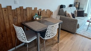 Ein Essbereich mit einem Holztisch und Stühlen, einer Holzvertäfelung an der Wand und einer Couch im Hintergrund.