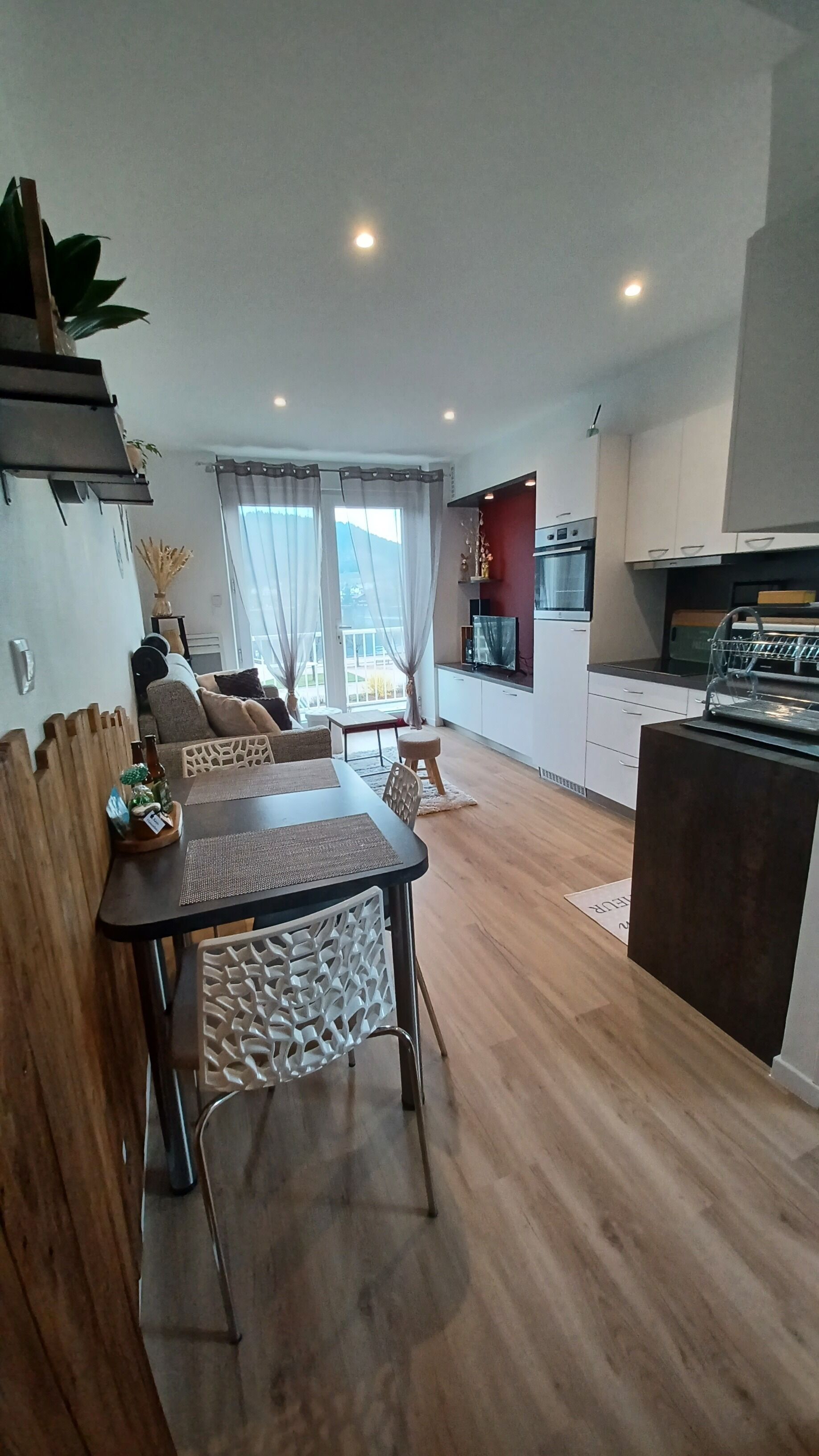 Une cuisine moderne avec un coin repas, un plancher en bois et une vue sur l’extérieur.