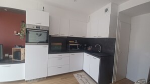 Eine kleine Küche mit weißen Schränken, einer schwarzen Arbeitsplatte, einer Mikrowelle und einer Kaffeemaschine.