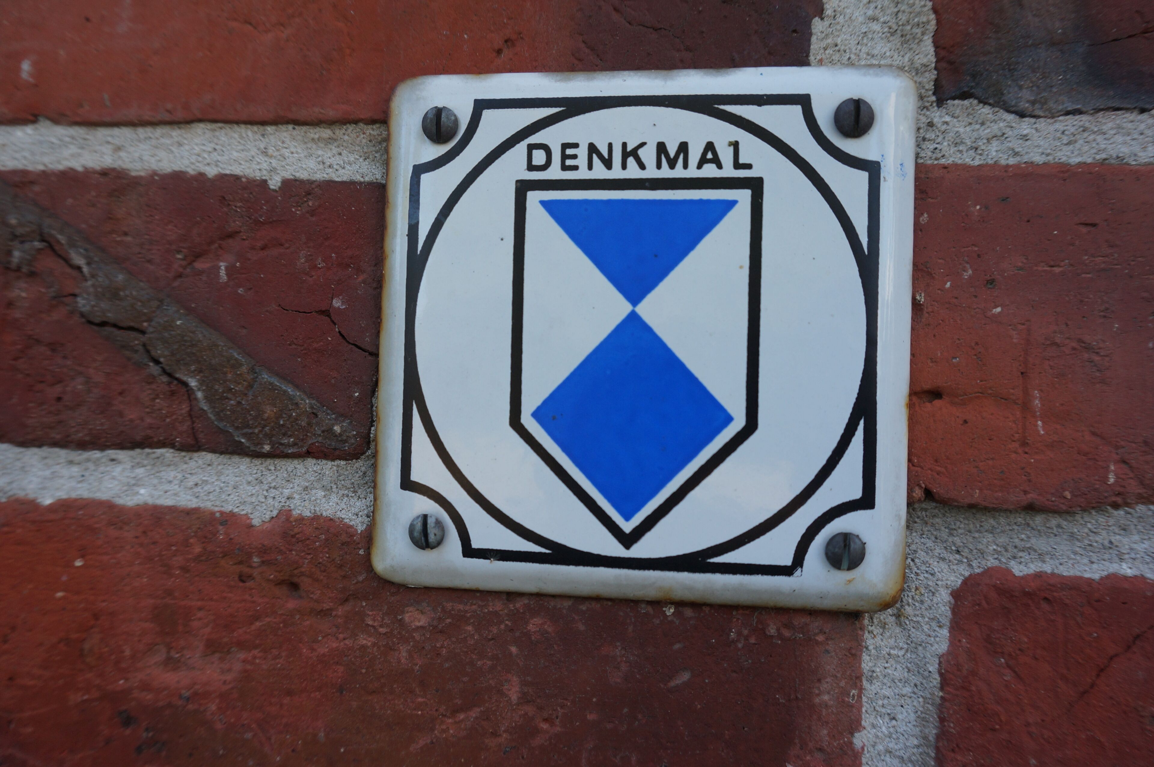 A DENKMAL sign mounted on a brick wall.