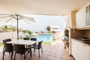 A patio area with a pool, outdoor seating, and a kitchen with a grill.