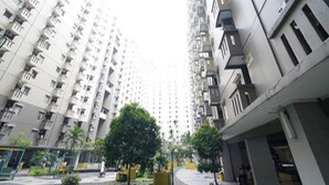 Un edificio residencial alto con varios balcones, un patio central con árboles y una senda peatonal.