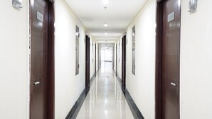 Un pasillo largo y estrecho con puertas a ambos lados, que conduce a habitaciones individuales.