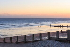 A beach with a wooden fence and a person walking a dog. - Beautiful 5 Bedroom Regency House / Pets Welcome (Bognor Regis)