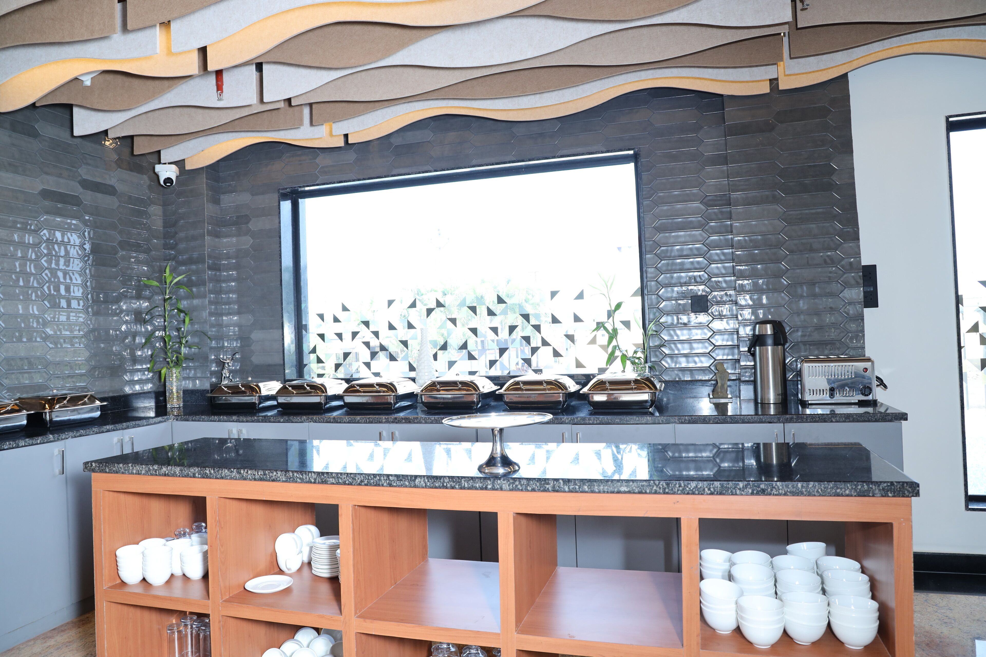 A modern kitchen with a black countertop, wooden shelves, and a large window.