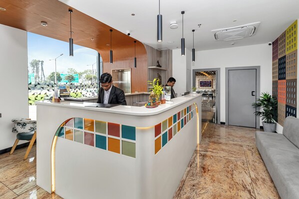 A modern reception area with a white counter, colorful mosaic tiles, and a wooden ceiling. - The Citi Residenci Hotel,Banskopa (Durgapur)