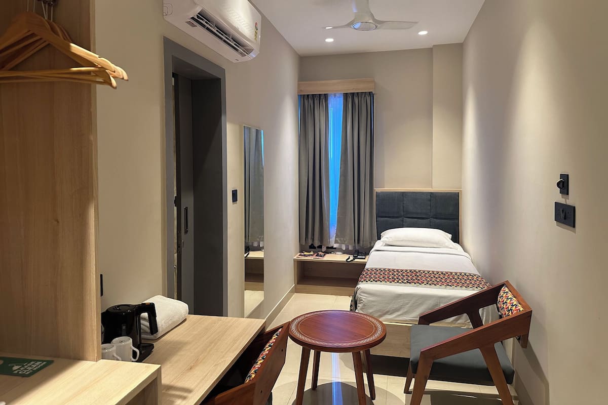 Ein Hotelzimmer mit Bett, Nachttisch, Stuhl und Klimaanlage.
