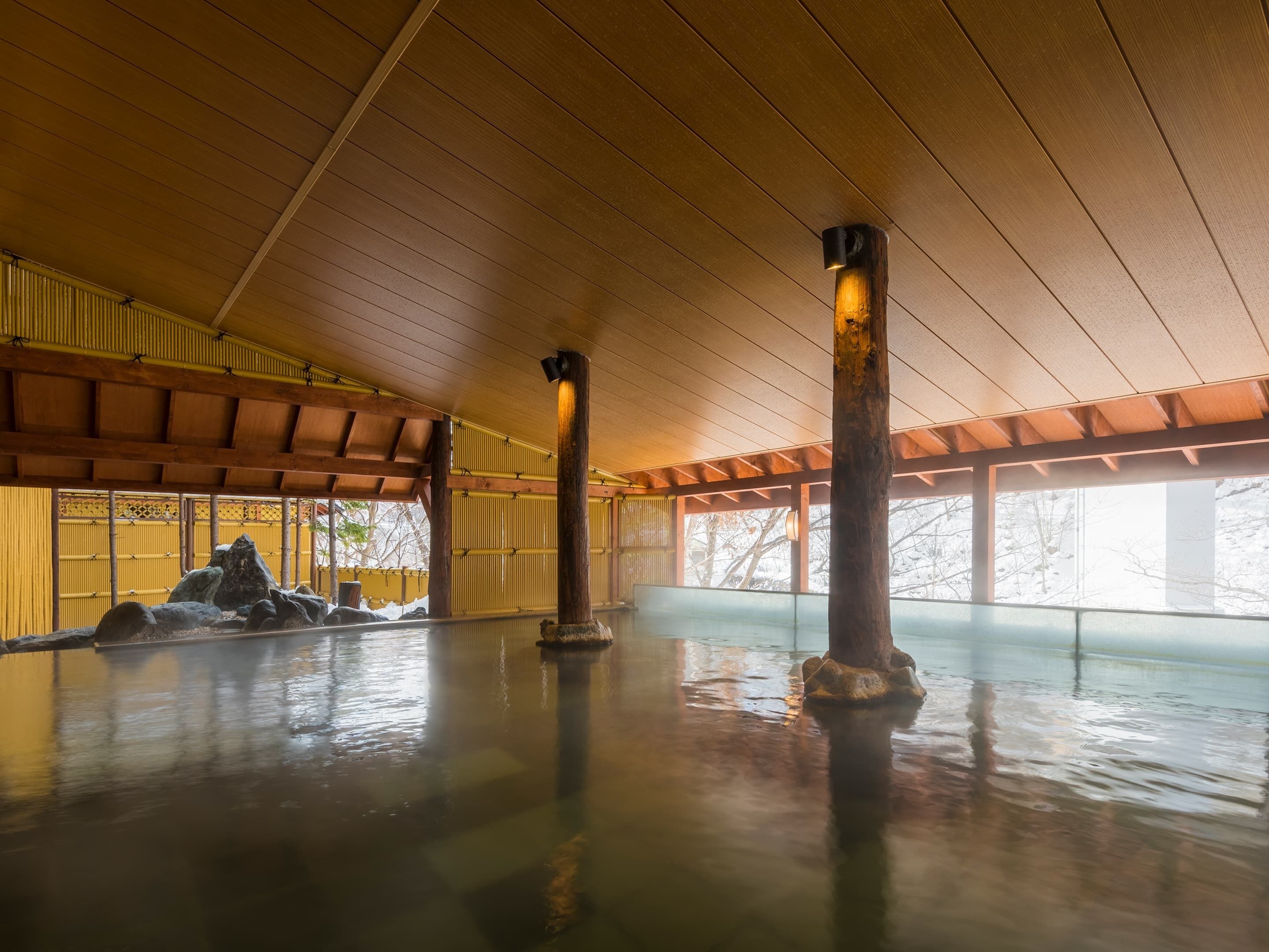 Ein geräumiger Innenbereich mit hohen Decken und Holzbalken, mit einem großen Wasserspiel und Felsformationen.