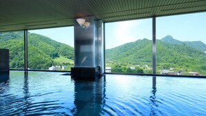 An indoor infinity pool with a view of lush green mountains. - EXECUTIVE SUITE SUIREI (Sapporo)