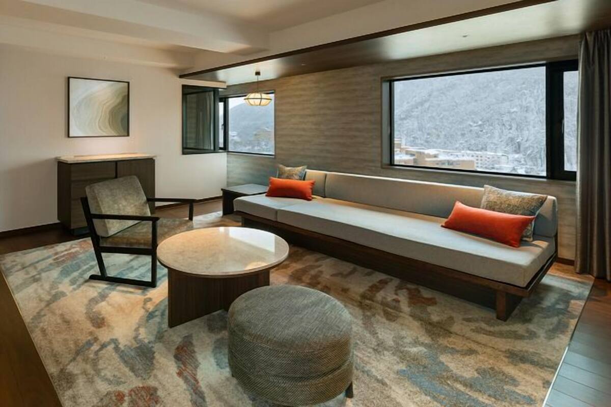 Una sala de estar moderna con un sofá, un sillón, una mesa de centro y un ventanal grande.
