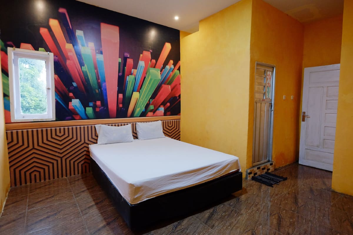 A room with a bed, a window, a door, and a colorful wall mural.