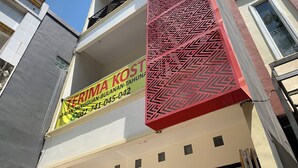 Une façade d’immeuble ornée d’un motif géométrique rouge bien visible et d’une enseigne jaune indiquant qu’un bien immobilier est à vendre.