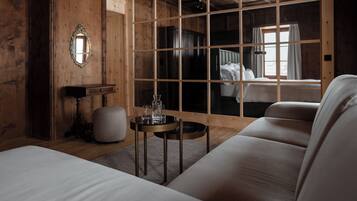 A wooden room with a bed, a sofa, a small table with glasses, and a mirror on the wall.