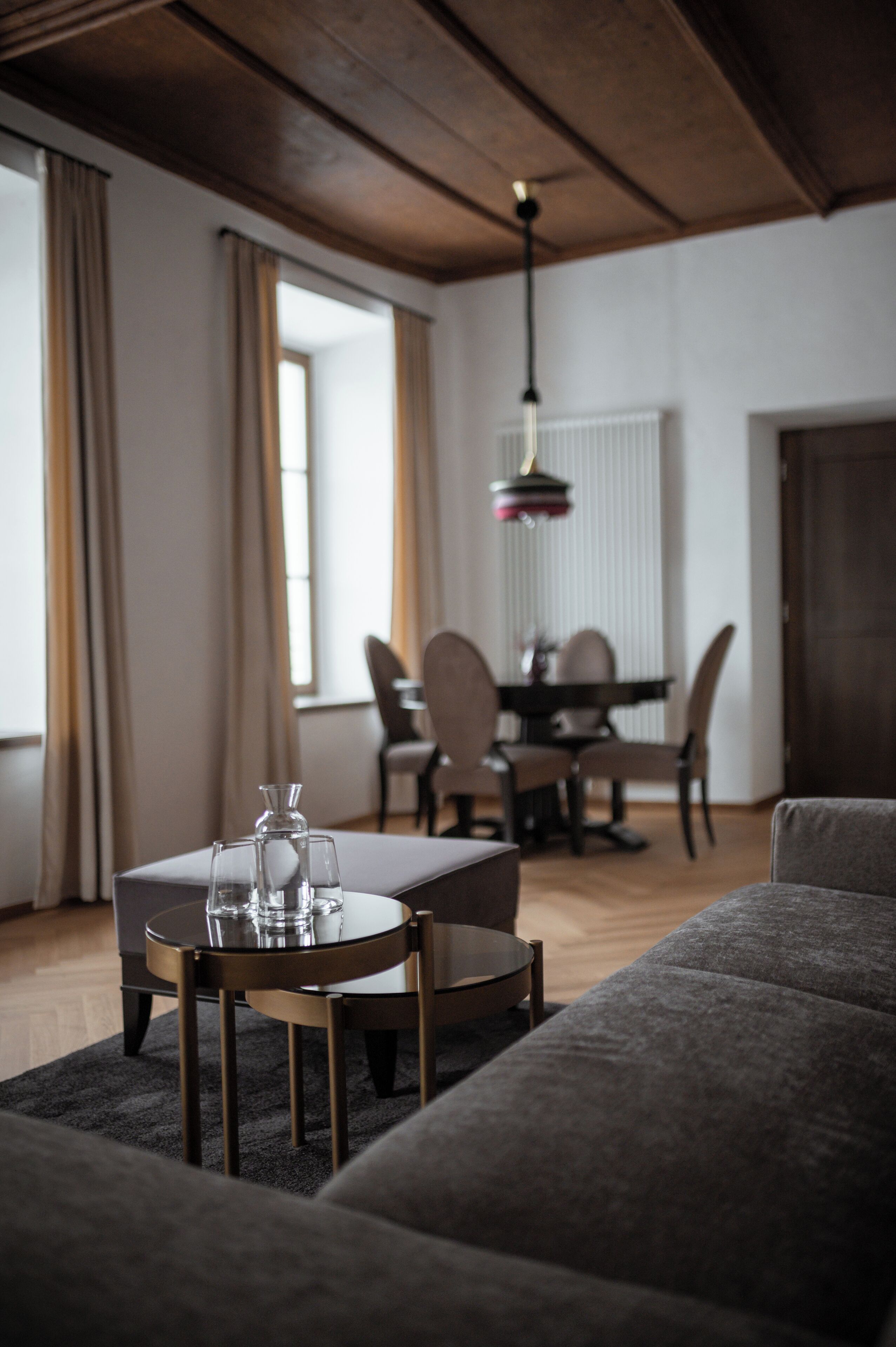 A modern living room with a round coffee table, a sofa, and a dining area in the background.