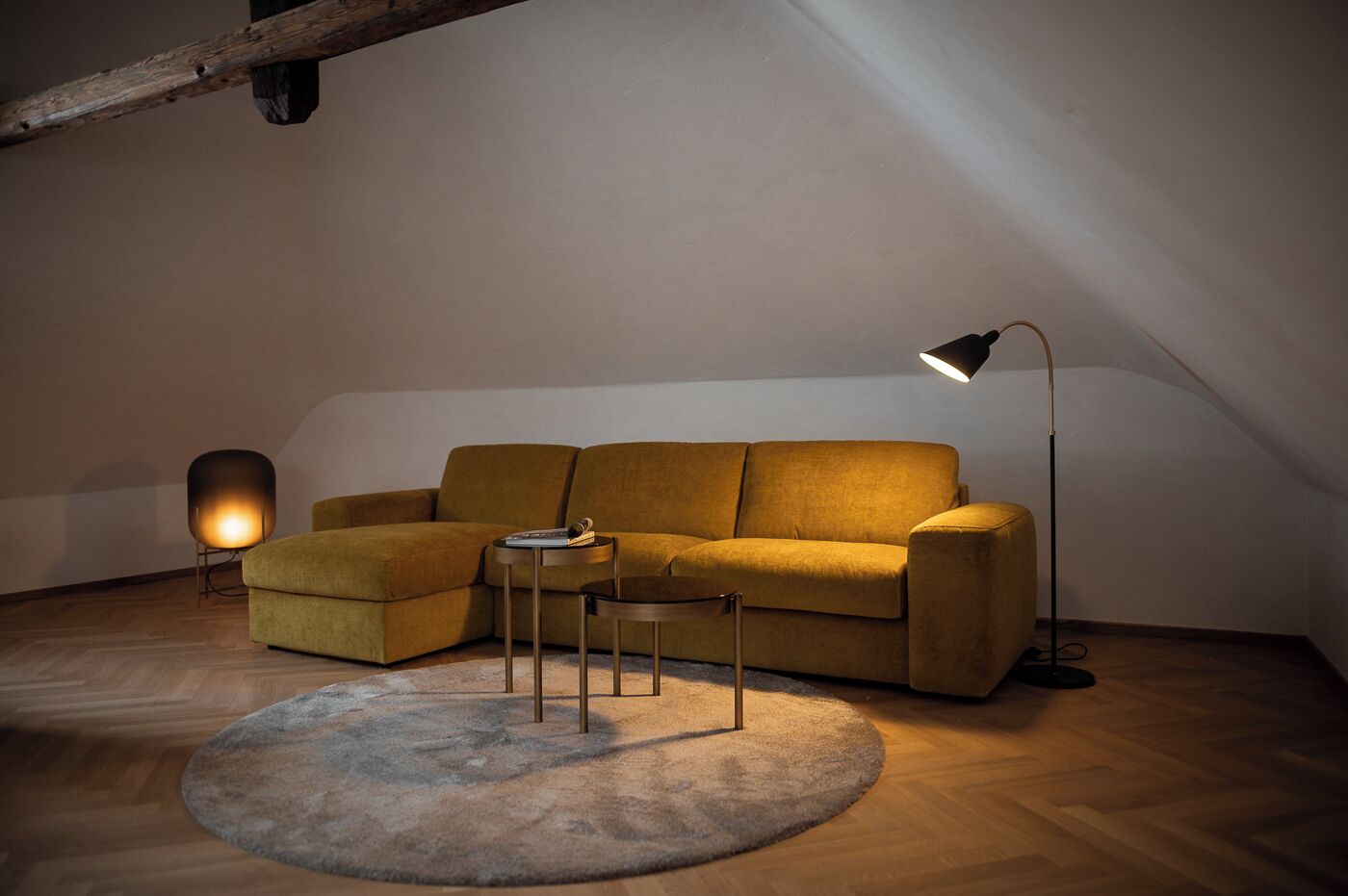 Ein gemütliches Schlafzimmer im Loft-Stil mit einer Couch, einem kleinen Tisch und einer Stehlampe.