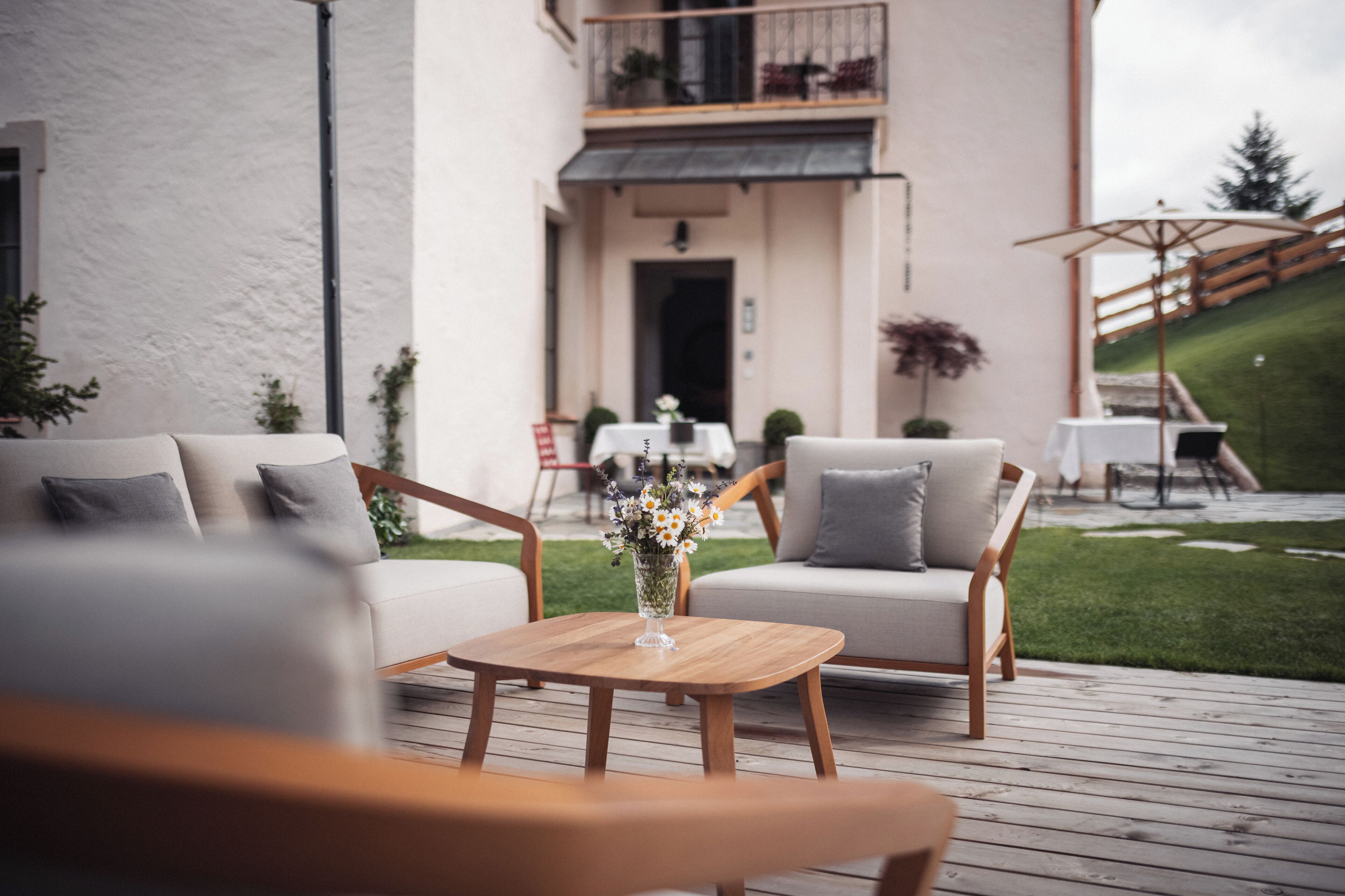 Terraza con dos sofás y una mesa, balcón con barandilla y entrada a un edificio.
