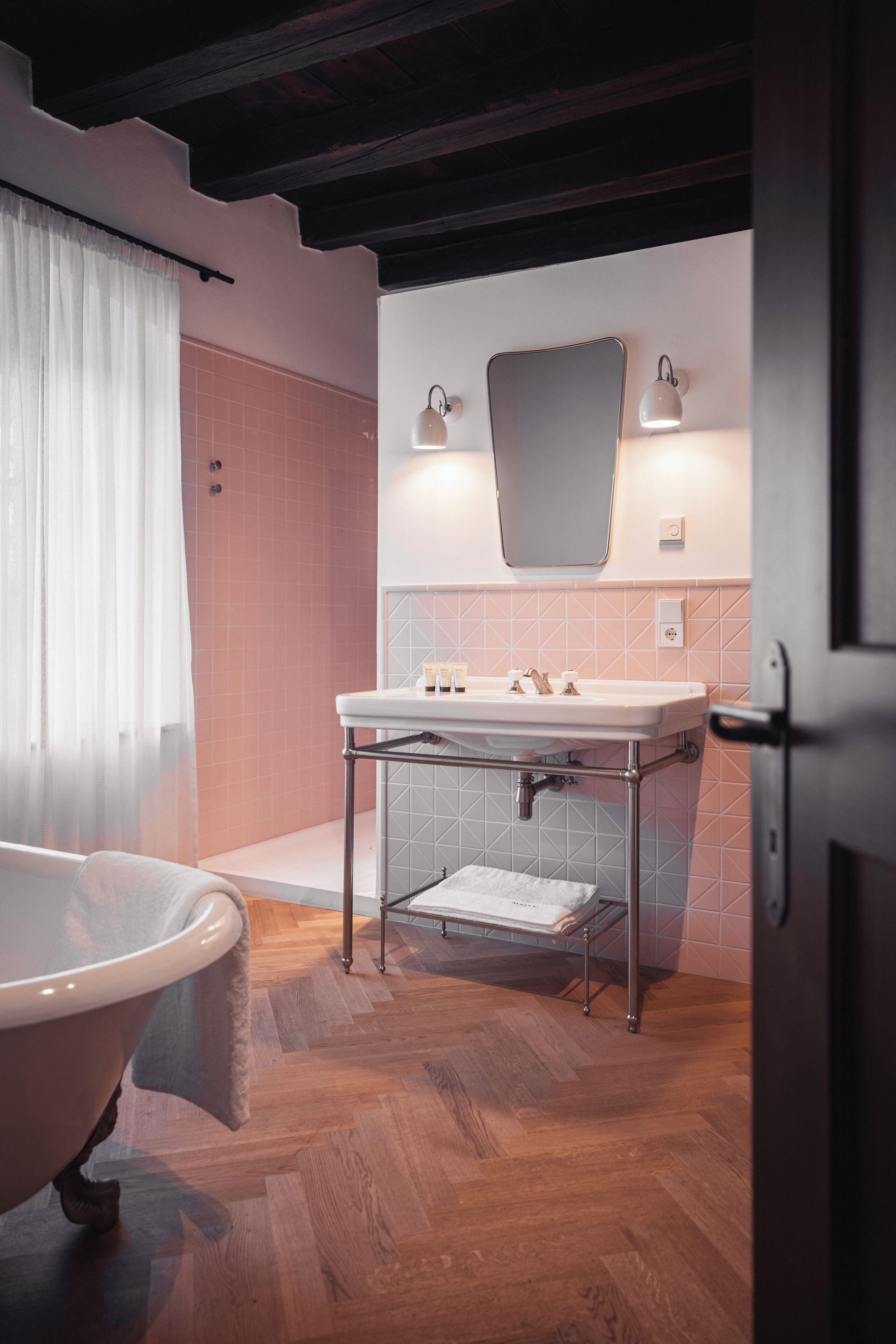 Un bany amb una banyera independent, un lavabo amb un mirall damunt i una zona de dutxa.