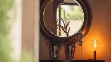 A bathroom vanity with a round mirror, a small potted plant, and a wall-mounted light fixture.