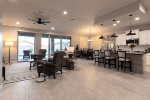 Un amplio salón con una mesa de comedor, sillas y una cocina equipada con electrodomésticos modernos.