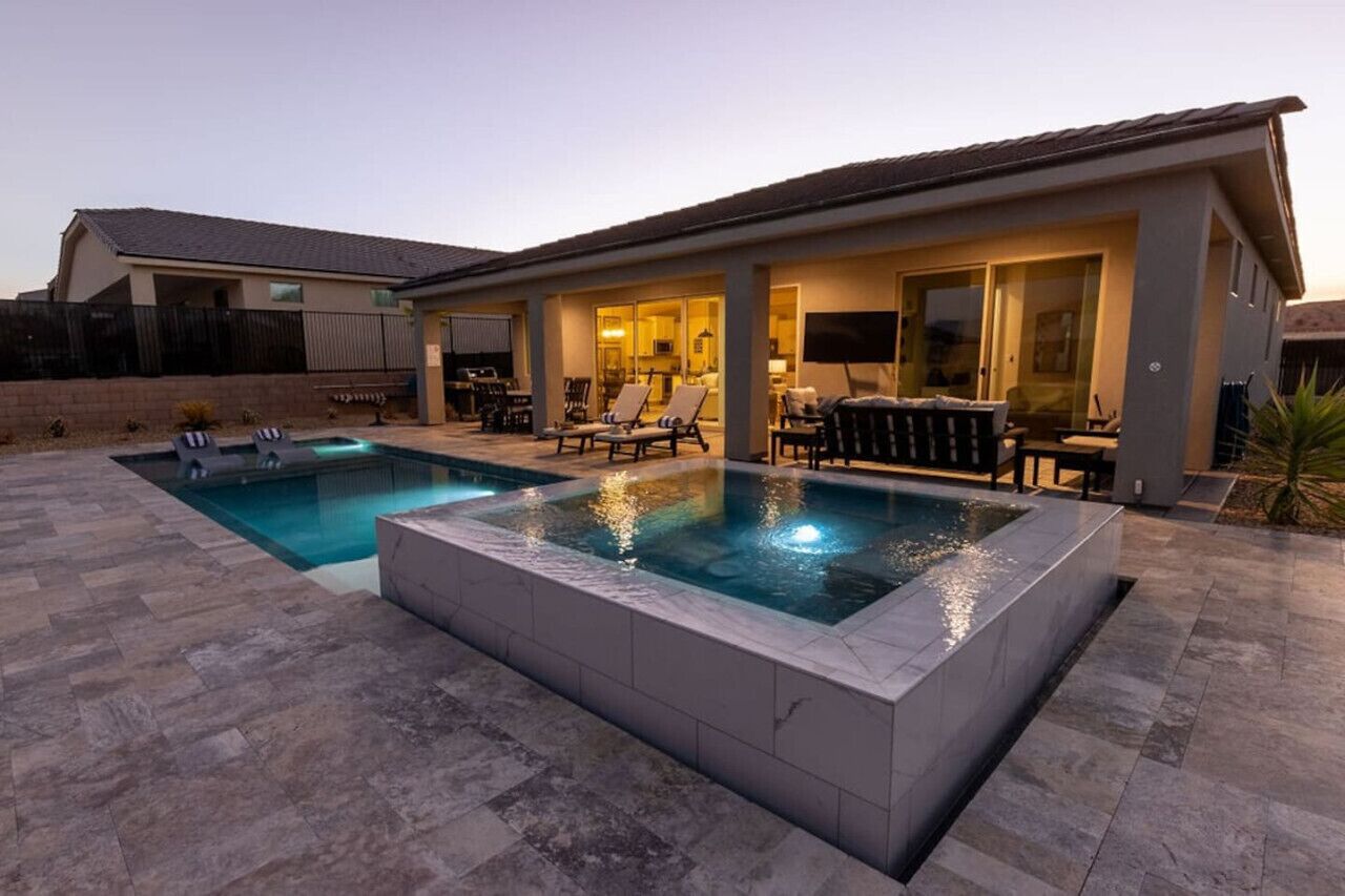 Une maison moderne dotée d’une piscine, d’un espace salon extérieur et d’une terrasse bien éclairée.