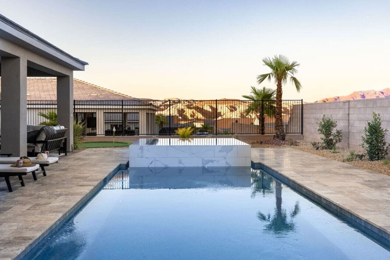 Piscina con un elemento decorativo de piedra, asientos exteriores y vistas a una cordillera.