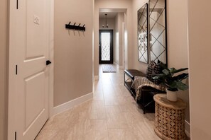 A hallway with a bench, a plant, and a door with a coat rack.