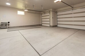 A spacious garage with concrete floors, metal garage doors, and overhead lighting.