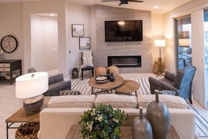 A living room with a fireplace, sofa, coffee table, and a TV mounted on the wall.