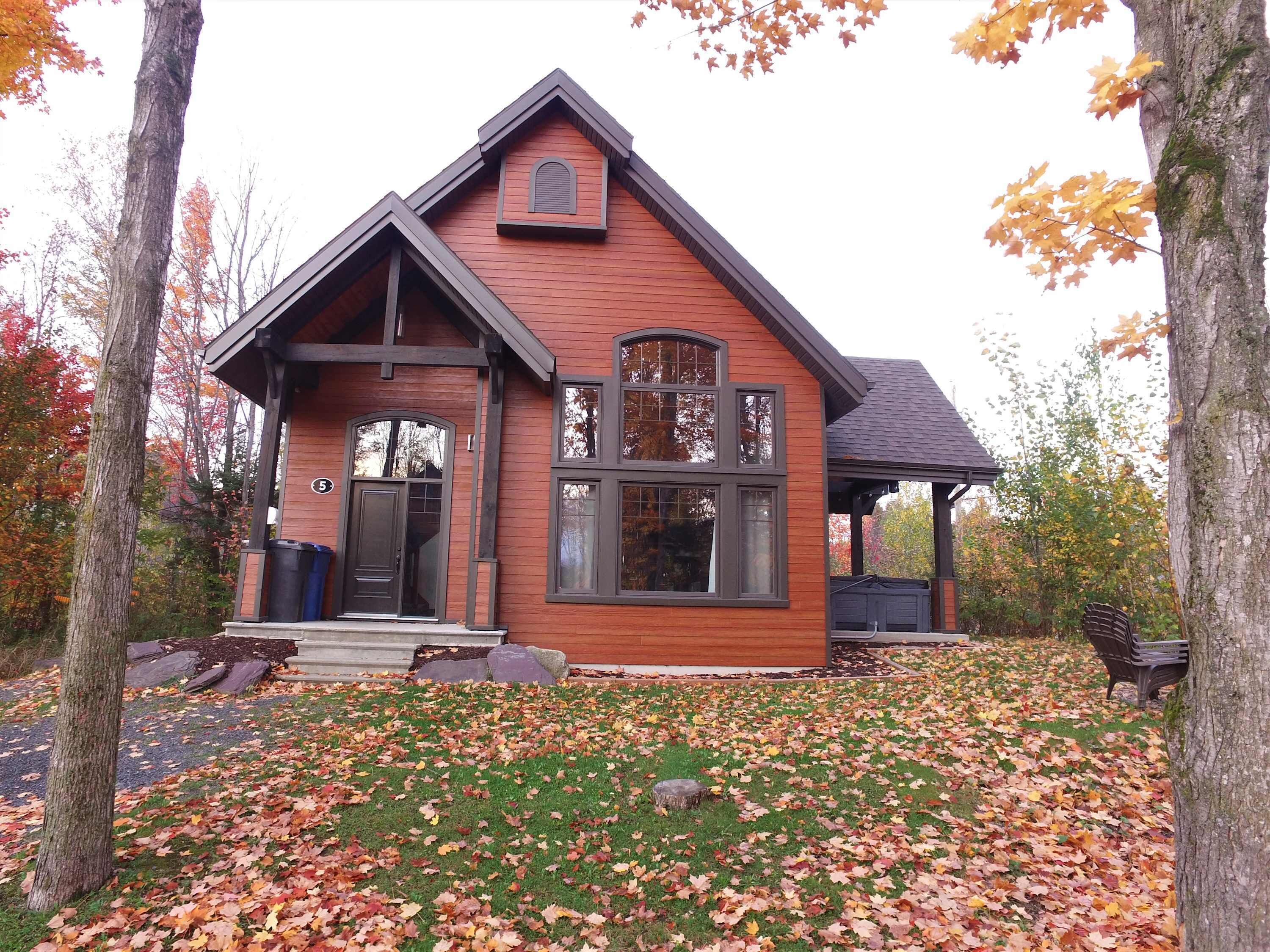 A two-story house with a prominent gable roof, a front porch, and a covered porch area.