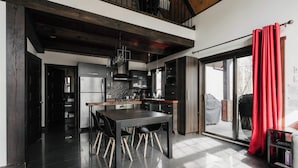 A modern kitchen with a dining area, featuring a large table and chairs, a built-in oven, and a sliding glass door leading to an outdoor area. - Family Chalet | SPA & Game Room | Le Bosquet (Scott)