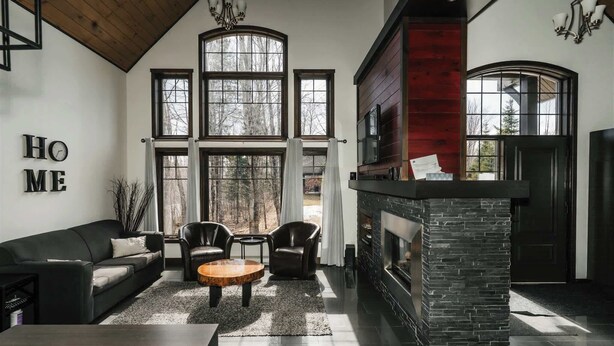 A modern living room with a fireplace, large windows, and a black leather sofa. - Family Chalet | SPA & Game Room | Le Bosquet (Scott)