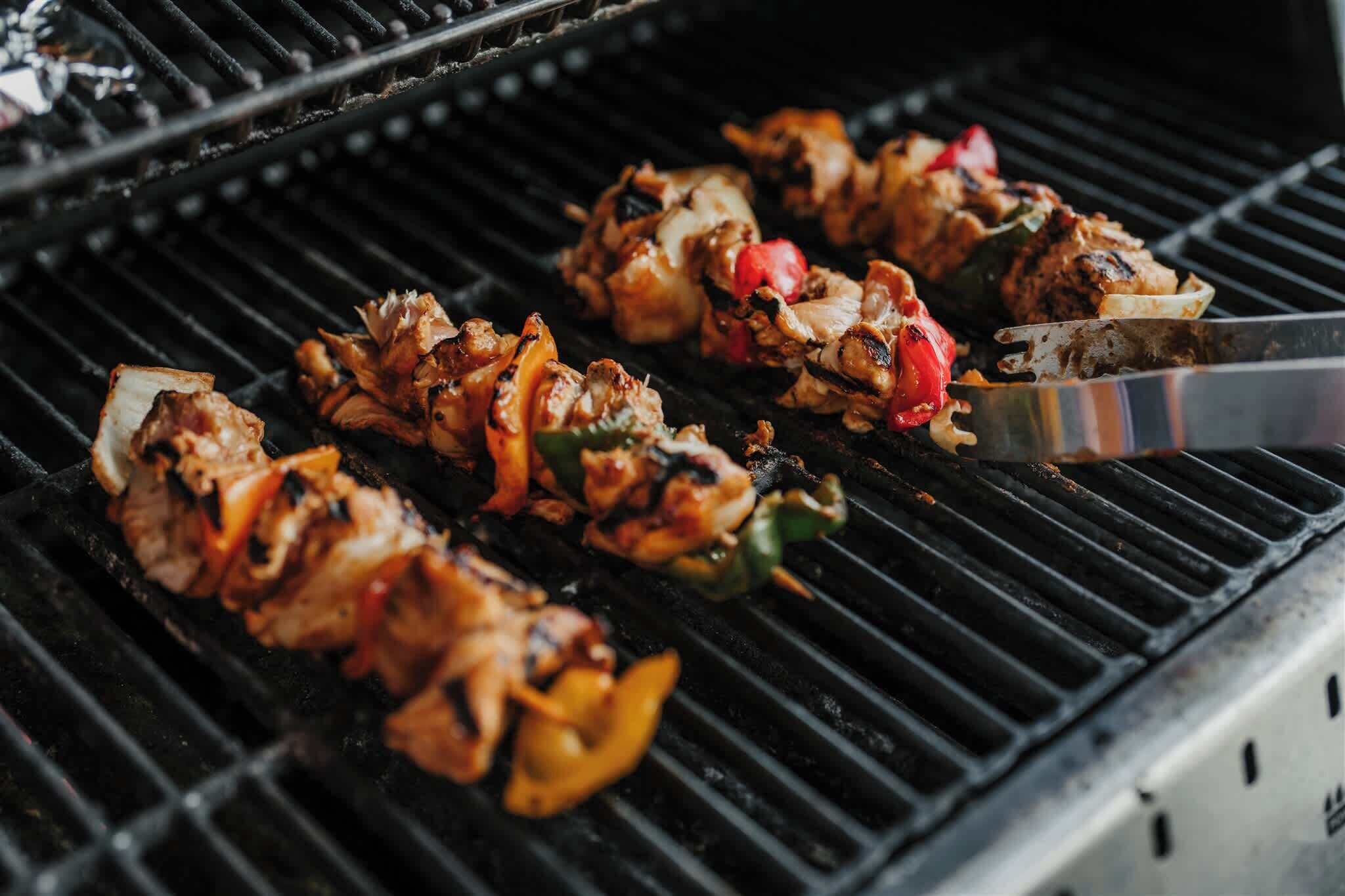 Een barbecue met spiezen vol vlees en groenten die worden bereid.