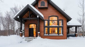 A wooden cabin with a steep gable roof, large windows, and a front porch. - Family Chalet | SPA & Game Room | Le Bosquet (Scott)