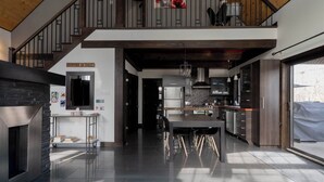 A modern kitchen with a central island, a dining area, and a staircase leading to an upper level. - Family Chalet | SPA & Game Room | Le Bosquet (Scott)