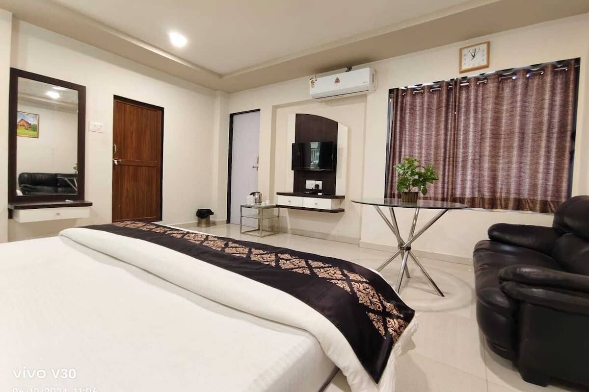 Quarto de hotel com cama, televisão, escrivaninha, cadeira e ar condicionado.